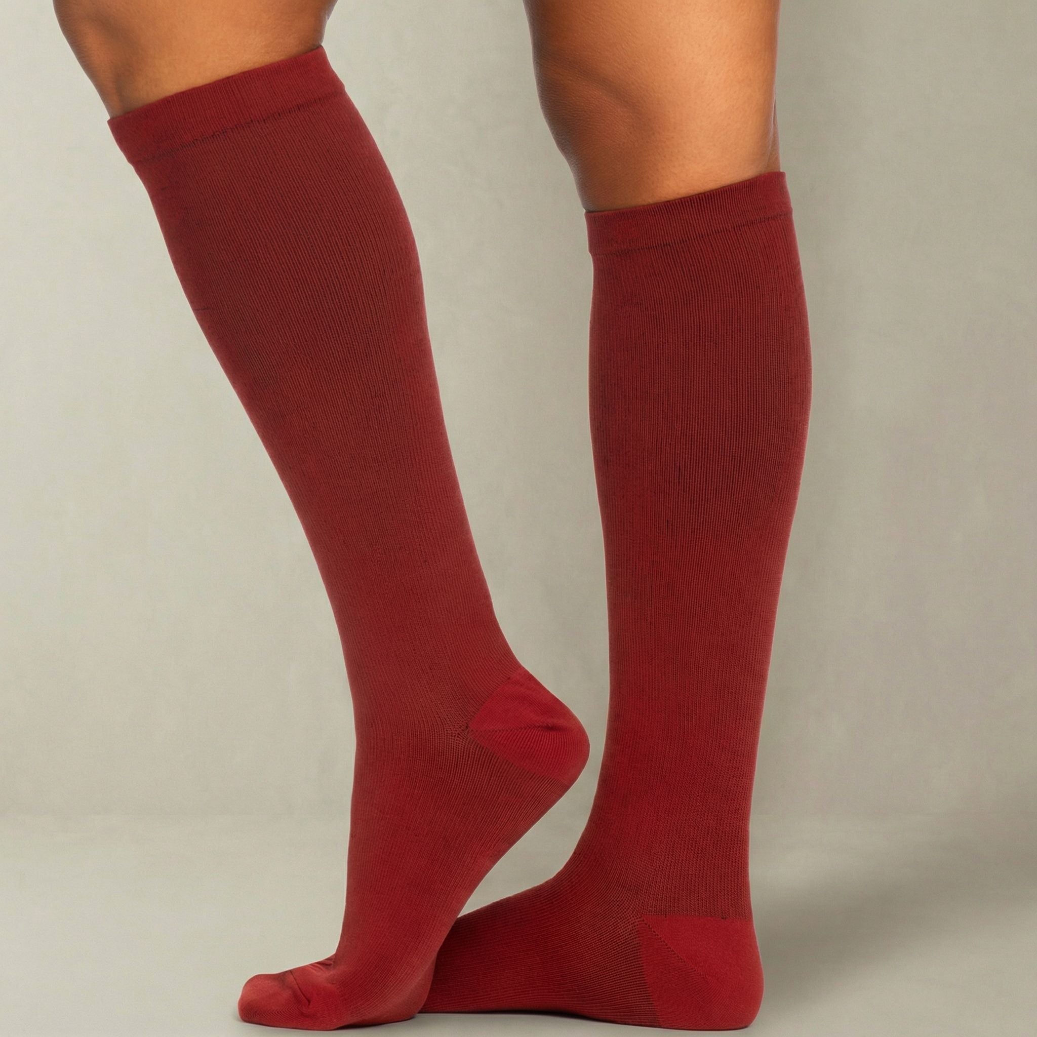 Burgundy compression knee-high socks worn by a person on a plain background