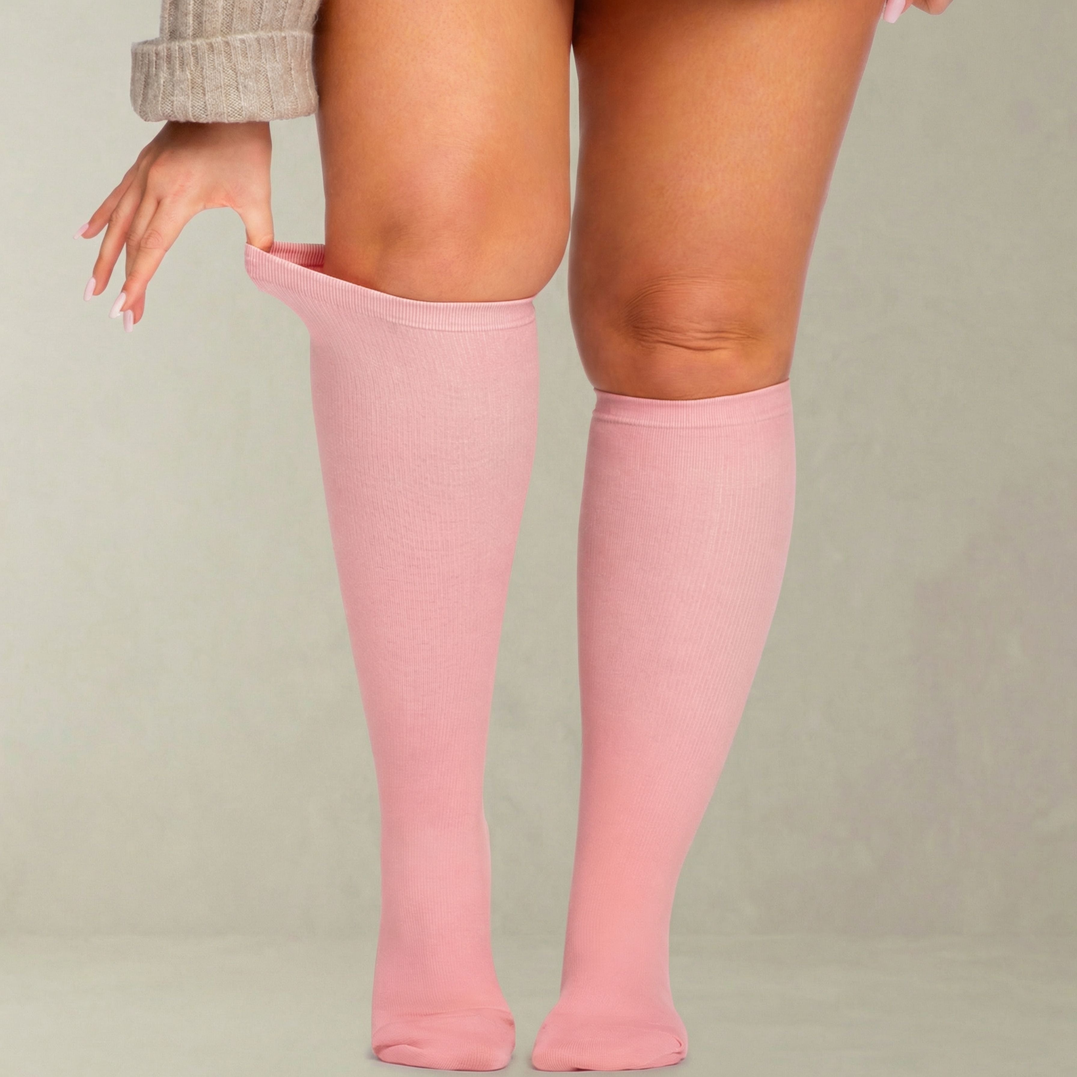 Person wearing pink knee-high compression socks on a plain background