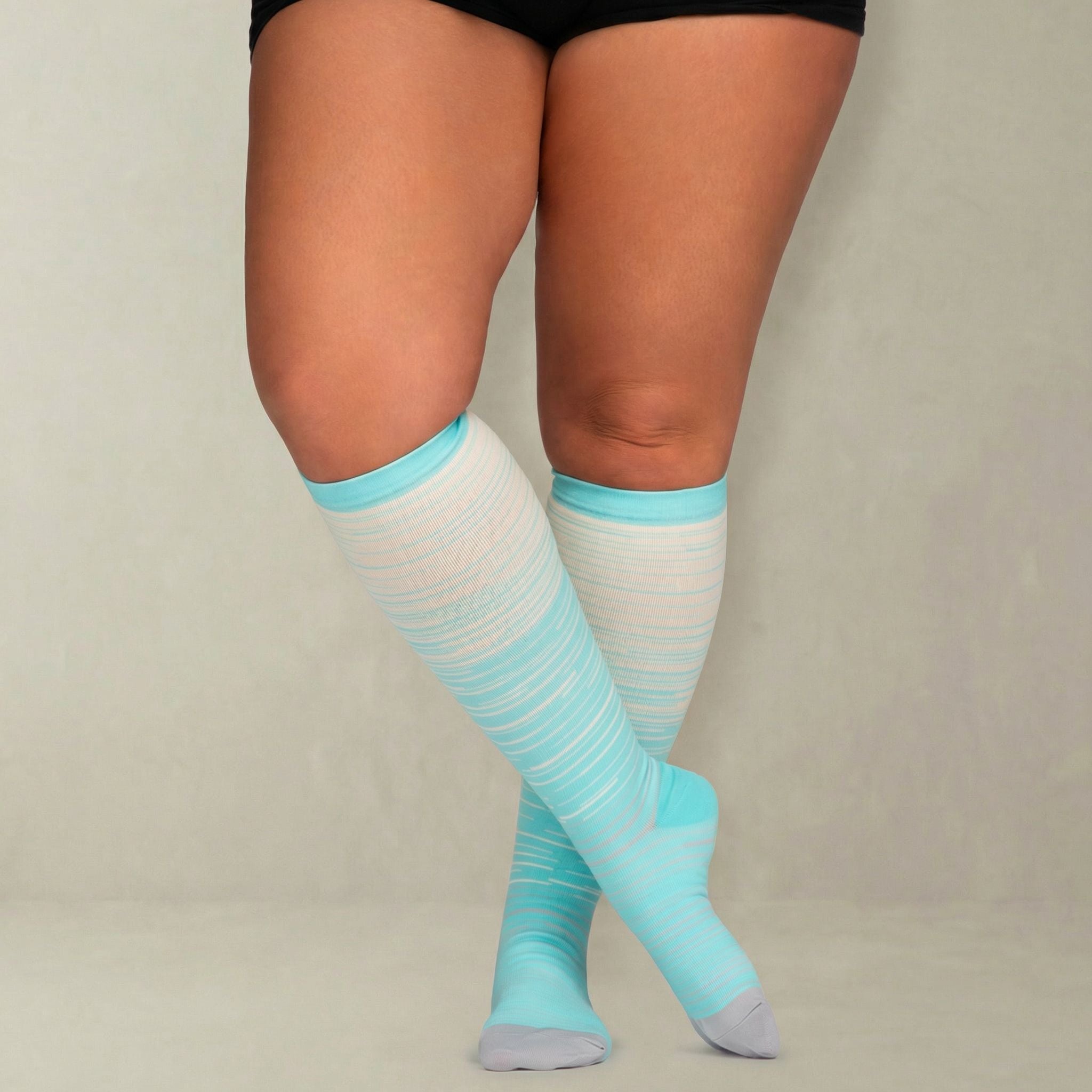 lightblue and cream striped compression socks worn by a person on a plain background