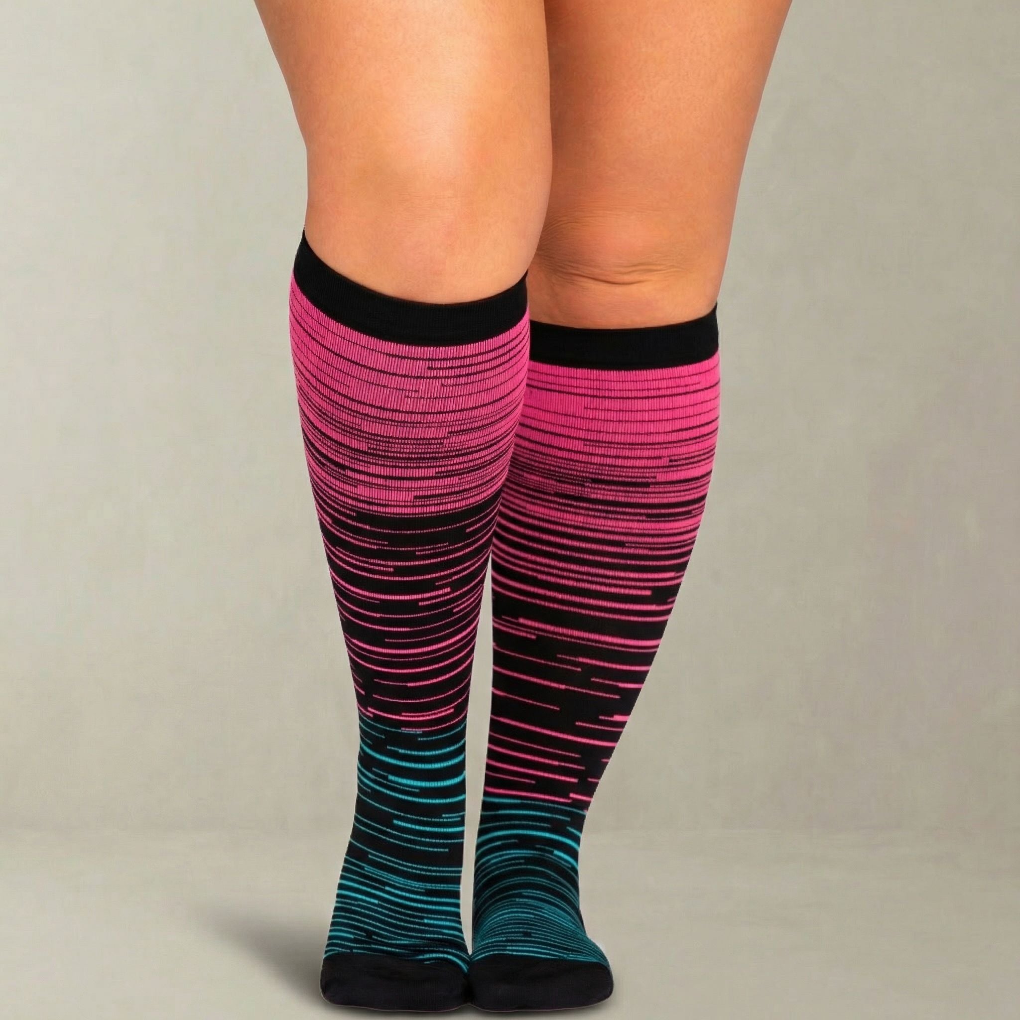 Knee-high compression socks with pink and blue striped pattern worn by a person on a neutral background