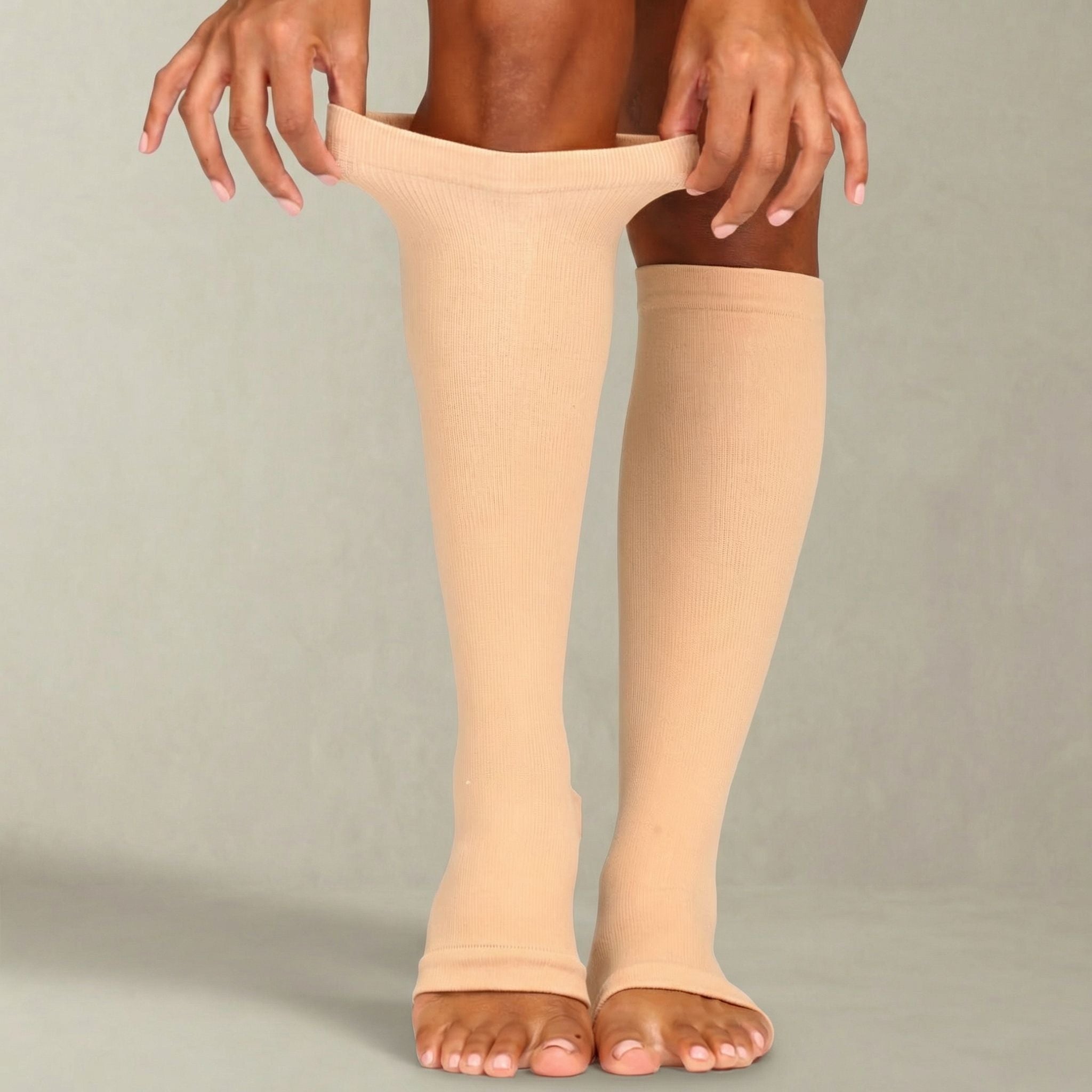Beige compression stockings being worn by a person on a plain background