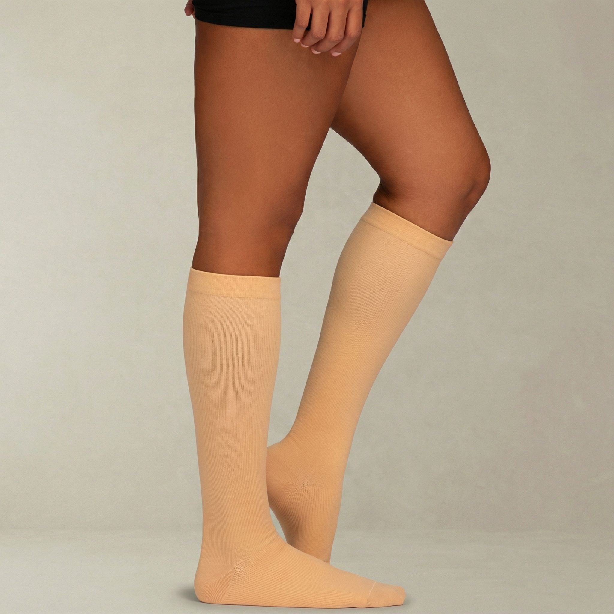 Beige knee-high compression socks worn by a person on a plain background