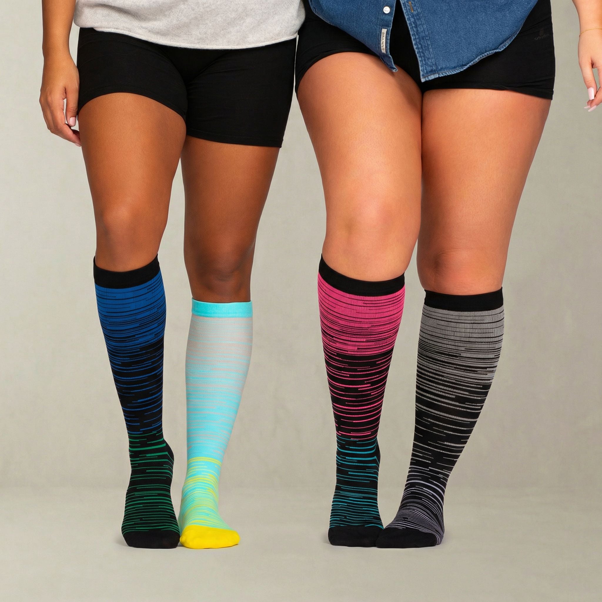 Two pairs of colorful knee-high compression socks worn by a person on a neutral background