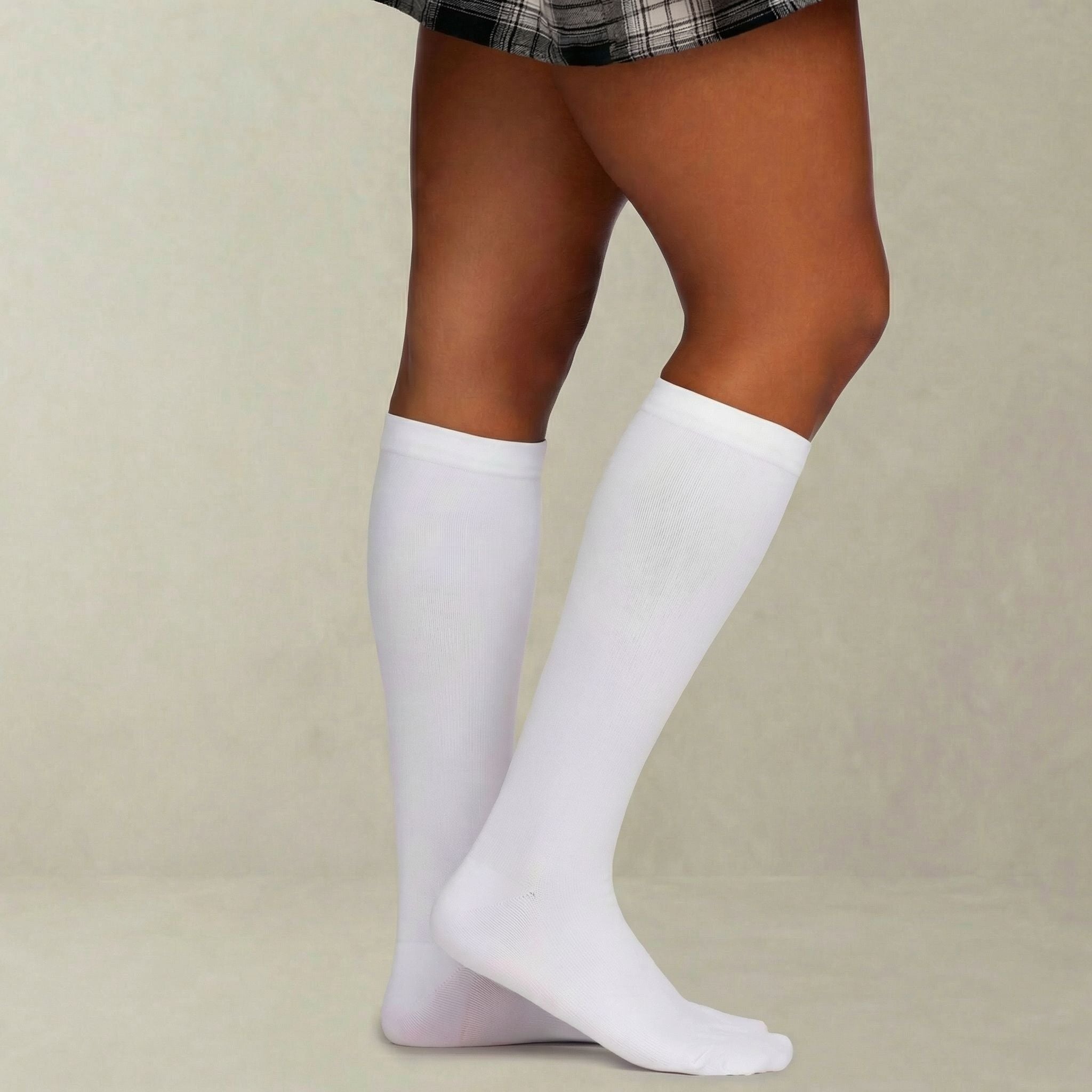 White knee-high compression socks worn by a person on a beige background