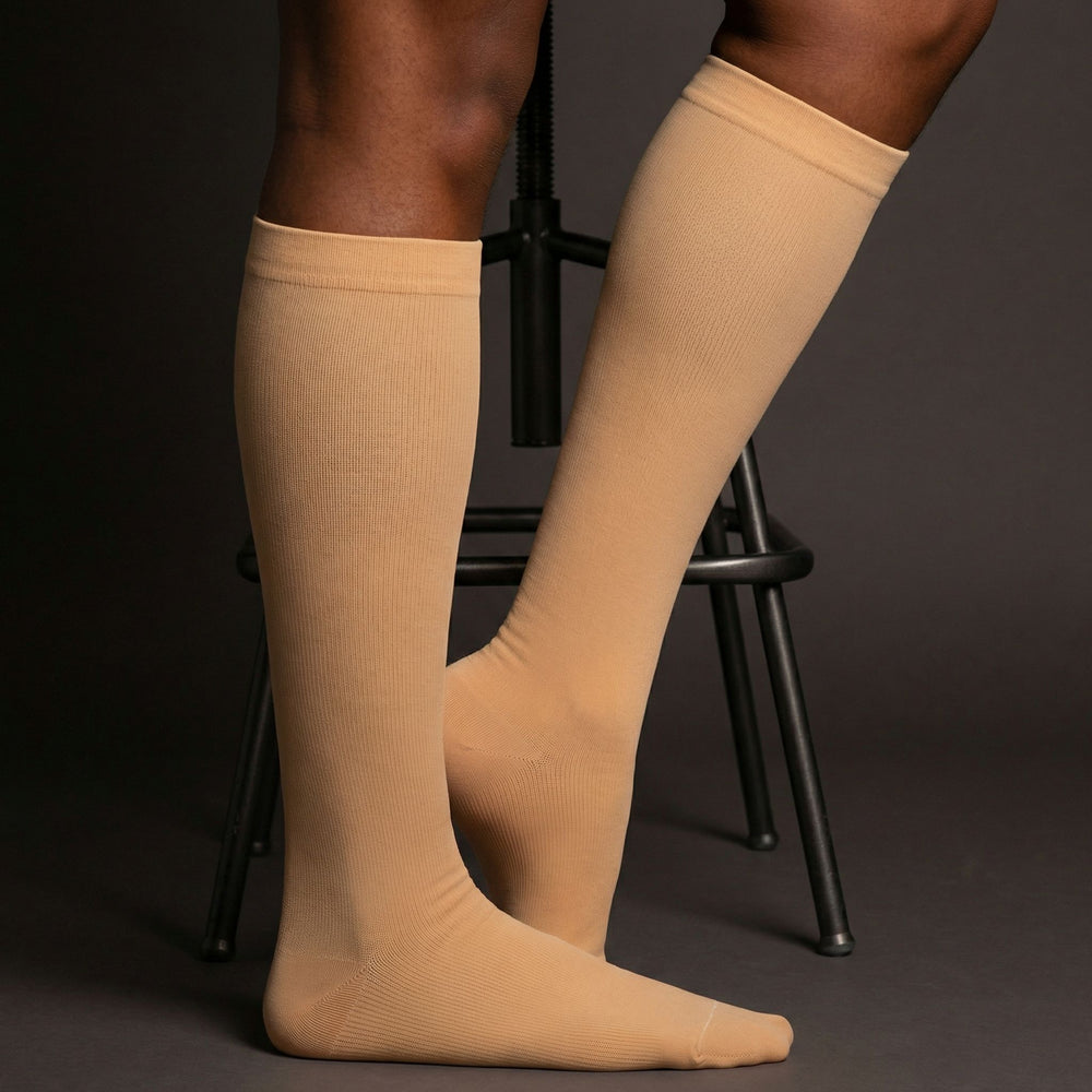 Beige compression knee-high socks worn by a person on a dark background