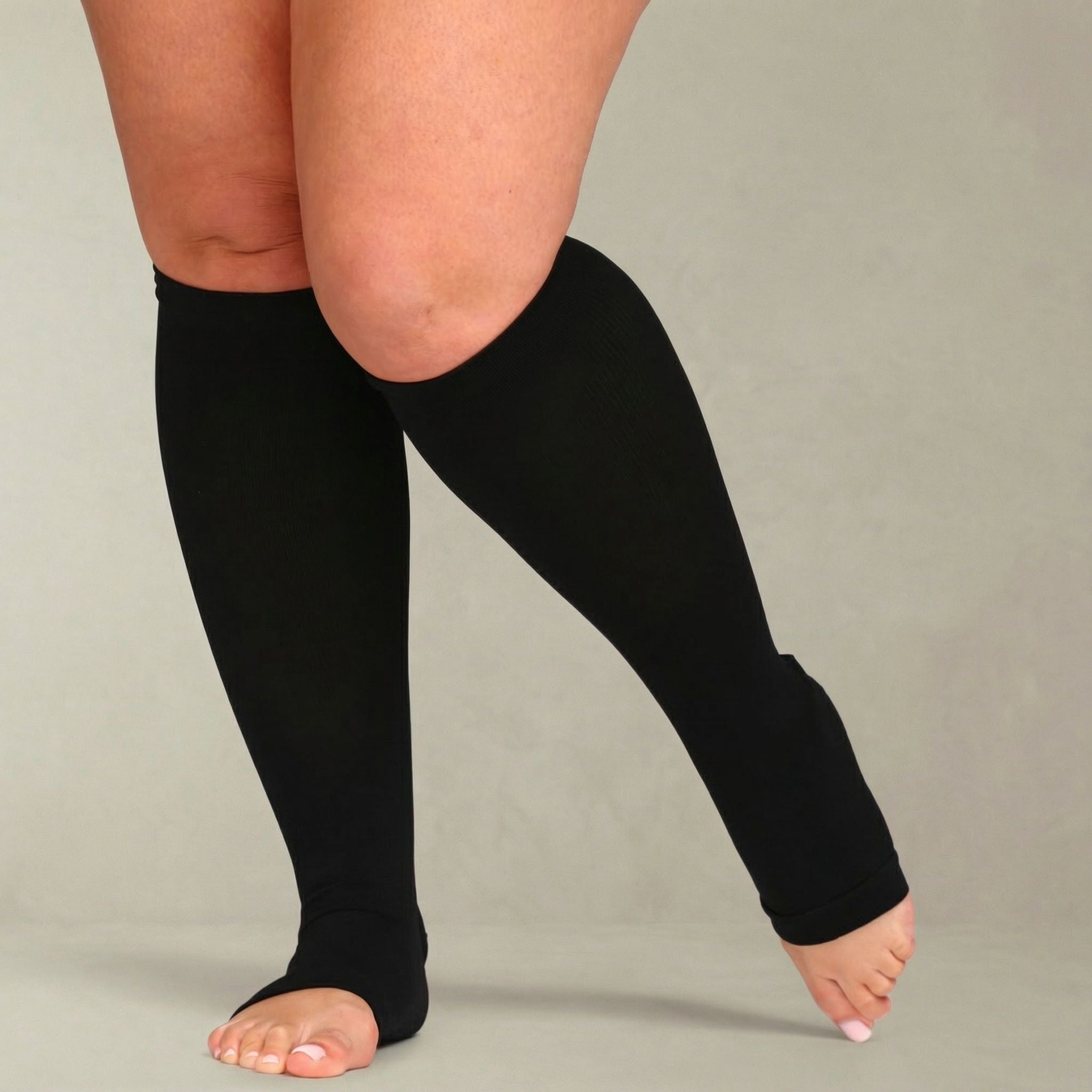 Person wearing black knee-high socks on a plain background
